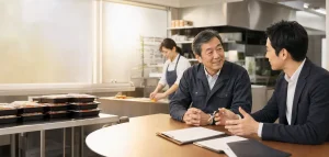 弁当製造会社のオーナーとM&Aアドバイザーが製造現場で相談している様子